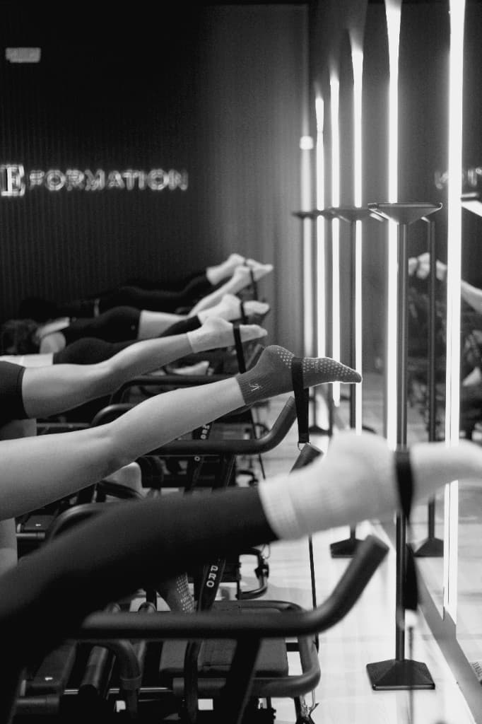 Lagree Formation studio: athletes training on Megaformers in a dramatic black-and-white class, Formation signage on the wall